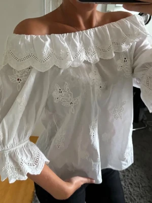Vit off-shoulder blus med brodyr - Superfin vit off-shoulder blus från & other stories med broderade blommor och volangkant upptill. Nypris 700kr och säljer i mycket bra skick! 🌷