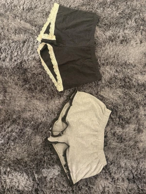 Två par shoets från H&M - Säljer två par shorts från H&M. Ett par är mörkgrå med vit spetskant och det andra är ljusgrå med svart volang.