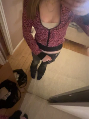 Rosa leopardmönstrad kofta - Säljer en rosa kofta med svart leopardmönster och svarta muddar. Koftan har långa ärmar och knäppning framtill. Perfekt för dig som vill sticka ut med en färgstark och trendig look.