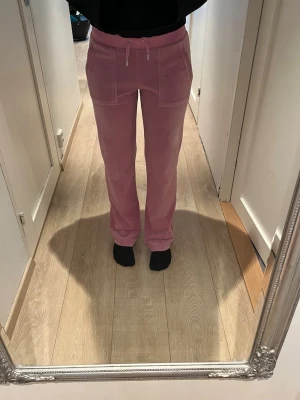 Rosa mjukisbyxor (Juicy byxor)  - Säljer ett par rosa mjukisbyxor med raka ben och bred resår i midjan. Perfekta för chill dagar eller när du vill vara bekväm. Mjukt material som känns skönt mot huden.