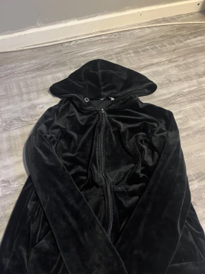 Svart zip hoodie från b.young - Säljer en svart hoodie i mjuk velour från b.young. Hoodien har dragkedja framtill, huva och långa ärmar. Perfekt för dig som gillar en chill och stilren look. Materialet är glansigt och känns riktigt skönt mot huden.