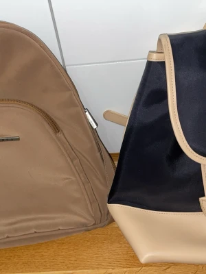 Beige ryggsäck från Adax - Jag säljer två snygga och praktiska mini-ryggsäckar:  ✨ Kanebo – stilren och smidig, perfekt för vardag och utflykter. ✨ D. Jones – elegant design med bra förvaring trots kompakt storlek.  ✔️ Båda i fint skick ✔️ Lätta och bekväma att bära ✔️ Perfekta när du vill ha med det viktigaste  Säljes tillsammans eller separat.