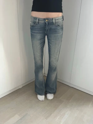 Blå bootcut jeans från Cheap Monday - Snygga ljusblå bootcut jeans från Cheap Monday med klassisk femficksdesign och gylf med knapp. Jeansen har en lätt tvättad look och en ikonisk logga på bakfickan. Perfekta för en avslappnad och trendig stil.