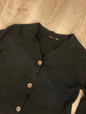 Svart kofta med träknappar - Mysig svart kofta från lager 157. Ser svart ut på bilden men är en väldigt mörk grön/ blå färg i verkligheten. 