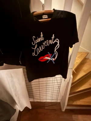 Svart Saint Laurent t-shirt - Snygg svart t-shirt från Saint Laurent med vit text och grafiskt tryck.