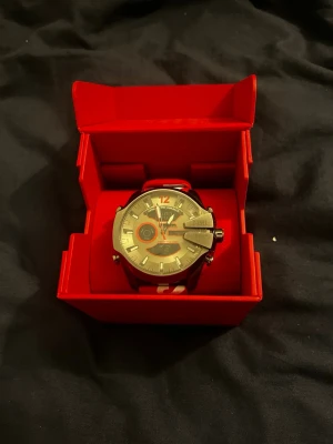 Diesel herrklocka DZ4647 silver/röd - Snygg herrklocka från Diesel, modell DZ4647. Klockan har en stor rund urtavla i silver med röda detaljer och markerade siffror. Kommer i en cool röd box som matchar de röda inslagen på klockan. Perfekt accessoar för dig som vill sticka ut.