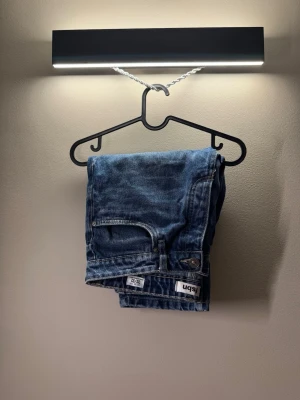 Blå jeans från 5bn - Säljer ett par klassiska blå jeans från 5bn med rak passform och normal midja. Jeansen har fem fickor och en snygg tvättad look som passar till det mesta. Materialet är slitstark denim i bomull. Perfekta för dig som gillar en enkel och tidlös stil.