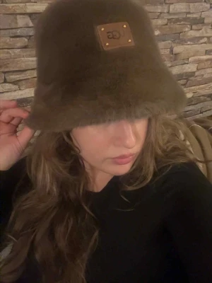 Brun bucket hat från UGG - Säljer en brun bucket hat från UGG med en fyrkantig läderpatch framtill. Hatten är gjord i ett mjukt och fluffigt material. Skriv privat vid flera frågor☺️♥️