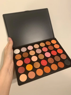 Stor ögonskuggspalett i varma toner - Säljer en stor ögonskuggspalett med 35 nyanser i varma färger som guld, röd, orange, sopiga bruna och rosa toner. Paletten har både matta och skimrande/glittriga skuggor i rund form. Perfekt för kreativa sminkningar och många olika looks.