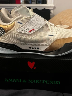 Li-Ning Wade 808 4 Ultra basketskor - Snygga basketdojor från Li-Ning, modell Wade 808 4 Ultra. Skorna är vita med detaljer i blekguld och har en cool design med kardborreband och grafiska mönster. Ovandelen är i syntetläder och textil, yttersulan i RB+TPU. Perfekta för dig som vill sticka ut på basketplanen.