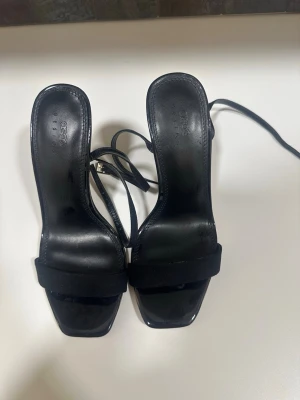 Svarta klackpumps med remmar från asos - Stilrena svarta pumps med fyrkantig tå och smala remmar runt vristen. Skorna har hög klack och en bred rem över foten. Tillverkade i en kombination av läder och mocka för en trendig look. Storleken är 37!🖤