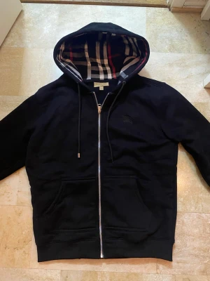 Burberry kofta - Säljer min burberry kofta som är typ helt ny. Bara använt några gånger. Den är i Large men känns mer som Medium. Ett problem med den är att den saknar en metall mot på snöret som man kan se på sista bilden. Pris går att diskuteras 