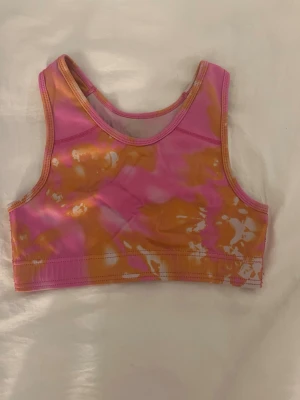 Rosa och orange tie-dye sport topp💞 - Snygg topp i sportig modell med tie-dye mönster i rosa, orange och vitt. Rund halsringning och breda axelband ger en bekväm passform. Perfekt för dig som gillar färgstarka underkläder med unik look. 💞