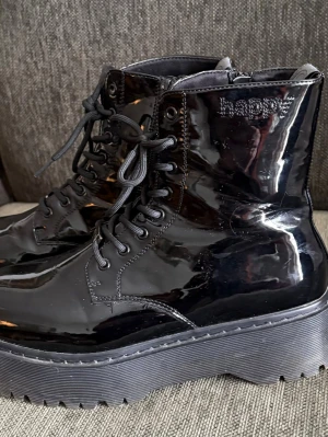 Lackkängor chunky - Svarta lackkängor med kraftig sula . Chunky-combat stil med snörning och dragkedja .storlek 41. Fint skick . Märket är Happy. 