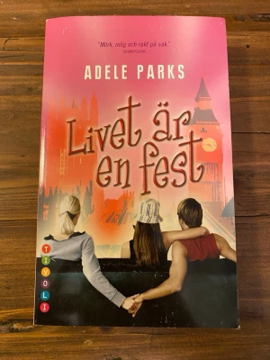 Livet är en fest av Adele Parks - En färgstark pocketbok med rosa och orange omslag, skriven av Adele Parks. Boken har titeln 'Livet är en fest' och handlar om relationer, hemligheter och kärlek. Omslaget visar tre personer på en bänk med London-silhuett i bakgrunden. Boken handlar om Bella som gifte sig i hemlighet med sin ungdomskärlek Stevie. Tio år senare träffar hon Philip i London. 