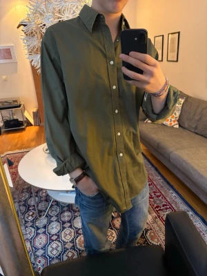 Olivgrön skjorta med knappar - Personlig favorit! Snygg olivgrön skjorta med klassisk krage och knäppning framtill. Skjortan har lång ärm och en relaxed passform.