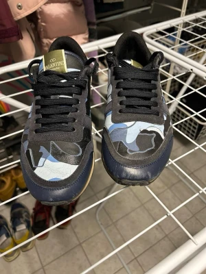 Valentino rockrunners - Säljer ett par snygga Valentino Rockrunners i en blå camofärg med vitt där bak. De är i ett bra skick och är i Storlek 40. 