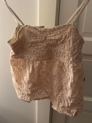 Beige spetslinne  - Säljer ett sött beige linne med tunna axelband och ett bubbligt spetsmönster. Toppen har en avslappnad passform och är perfekt för att skapa en romantisk look. Materialet är lätt och luftigt, vilket gör den skön att bära under varma dagar. Storlek 170 men sitter som en xs! Skriv för bild på🥰