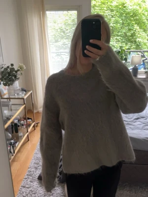 Stickad tröja i Mohairmix  - Superfin stickad tröja i en mjuk och lurvig kvalitet med mohair och ull. Tröjan har en gråbeige nyans som är lätt att matcha och passar lika bra under höst och vinter som under svala sommarkvällar. Perfekt som ett extra lager året runt.  Säljs i mycket fint skick då den tyvärr inte har kommit till användning!💗