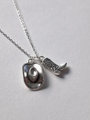 Silvrigt med cowboyhatt och cowboyboots 🤠 - Silvrigt halsband med två hängen: en detaljerad cowboyhatt och en westernstövel. Kedjan är tunn och smidig, och motiven ger en cool westernvibe till din stil Yeehaa 🤠 materialet rostfritt stål. 