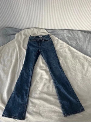 Blå bootcut jeans  - Snygga blå bootcut jeans med klassisk femficksdesign och utsvängda ben. Jeansen har medelhög midja. Innerbenslängden är Ca 83 cm. Lite smått slitna längst ner men annars i jättefint skick.