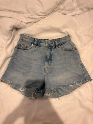 Ljusblåa jeansshorts med fransig kant - Snygga ljusblåa jeansshorts med hög midja och fransig kant från monki storlek 24.skriv vid intresse eller frågor 🩵 