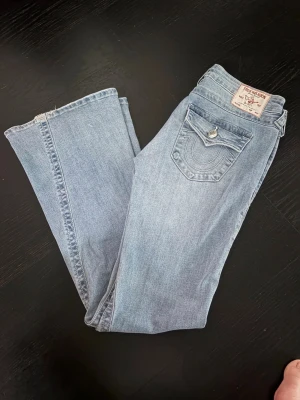 True Religion bootcut jeans strl.27 - True Religion jeans, modell Joey low rise flare, med klassiska sömmar och fickdetaljer bak. Strl.27, långa på min dotter som är 173cm. Jeansen har en knappstängning och gylf fram. Stretch i denim.