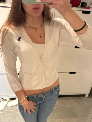 Vintage abercrombie & fitch trekvarts kofta - Abercrombie & Fitch i krämvit färg – vintage kofta med 3/4-ärmar! Storlek S! Bra skick, förvänta dig små defekter som syns på de sista bilderna. Passar perfekt med en topp under! Har knappar, små fickor, 3/4-ärmar och Abercrombie & Fitch älglogga. Följ för fler liknande kläder och köp bundle!