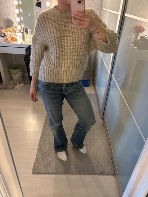 Beige chunky stickad tröja - Säljer en beige chunky stickad tröja med grov ribbstickning och rund hals. Tröjan har en avslappnad passform och långa ärmar, perfekt för lager på lager. Passar dig som gillar en mysig och trendig stil.
