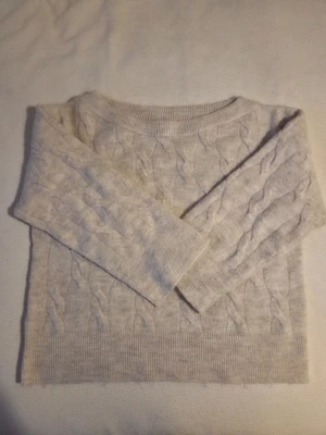 Beige kabelstickad off shoulder tröja från gina tricot - Mysig beige kabelstickad tröja med rund halsringning och ribbade muddar vid ärmslut och nederkant. Tröjan har ett klassiskt flätmönster och är tillverkad i ett mjukt material som passar perfekt för kyligare dagar.