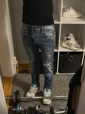 Blåa replay anbass - Säljer ett par blå skinny jeans med slitningar och tvättade detaljer på låren och knäna. Jeansen har fem fickor och dragkedja med knapp. Perfekta för en avslappnad och trendig stil. Har ett litet hål i skrevet syns knappt 