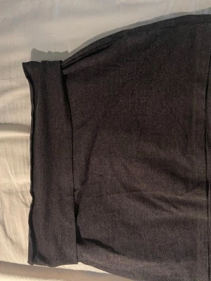 Mörkgrå kjol från Indiska - Mörkgrå kjol från Viskin med bred resår i midjan för extra komfort. Materialet är mjukt och stretchigt, perfekt för en avslappnad och snygg look. Passar dig som vill ha ett enkelt basplagg med stilren design.