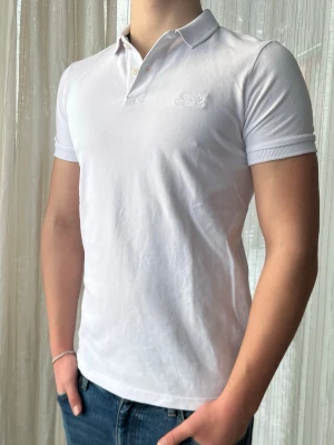 Vit Superdry piké, storlek S - Clean vit Superdry piké med vit logga i bomull perfekt till sommaren och våren                   Mycket bra skick, endast lite smuts på insidan vid kragen, annars som ny