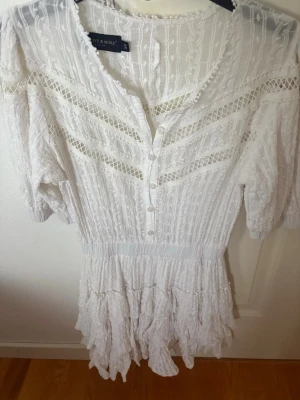 Studentklänning  - Superfin vit kortklänning i spets från Style & More. Klänningen har knappar framtill, volangdetaljer nertill och korta ärmar. Den är perfekt till stundenten eller skolavslutning🤍