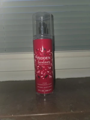 Hidden Fantasy Body Mist Britney Spears - Hidden Fantasy från Britney Spears är en body mist i en snygg röd plastflaska med genomskinligt lock. Flaskan har vita och rosa detaljer med fantasifulla motiv och text. Innehåller 236 ml och har en sprayfunktion för enkel applicering. Finns 90% kvar.
