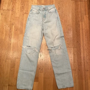 Ljusblå ripped jeans från Gina Perfect Jeans - Ljusblå jeans från Gina Perfect Jeans med raka ben och slitna detaljer över knäna. Klassisk femficksmodell med normal passform och snyggt stentvättad finish. Perfekta för en avslappnad streetstil.