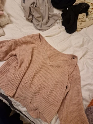 Beige stickad tröja Gina Tricot - Säljer en beige stickad tröja från Gina Tricot med v-ringad hals och bred ribbstickning. Tröjan har långa ärmar och en avslappnad, lite croppad passform. Perfekt att matcha med jeans eller kjol för en snygg vardagslook.