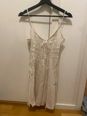 Randig vit kortklänning med smala axelband - Söt kortklänning i vitt med tunna beige ränder och smala axelband