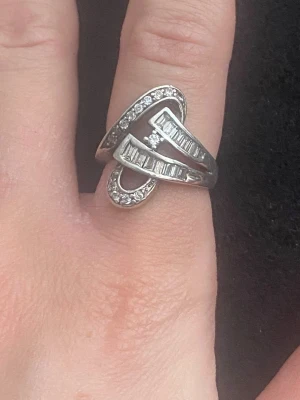 Snygg silverring med stenar - Unik silverring i 925 sterling silver med coolt, böljande design och infattade klara stenar i både runda och rektangulära former. Ringen har en modern look och gnistrar snyggt i ljuset. Perfekt för dig som gillar statement-smycken.