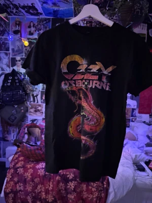 Ozzy Osbourne svart band-tshirt - Svart t-shirt med färgglatt tryck av Ozzy Osbourne och en stor orm på framsidan. Klassisk rund hals och korta ärmar. 