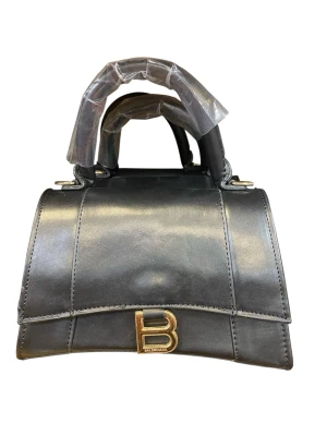 Svart  handväska i läder - Snygg svart handväska  i slätt läder med guldfärgat spänne framtill. Väskan har en stilren, strukturerad form och ett kort handtag. Perfekt för dig som gillar exklusiva accessoarer och vill sticka ut med en ikonisk design.