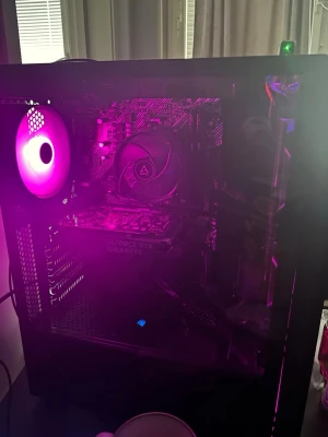 Stationär gamingdator med RGB-belysning - Säljer en stationär dator med svart chassi och snyggt mönstrad frontpanel. Invändigt finns RGB-fläktar och komponenter som ett GIGABYTE GeForce RTX-grafikkort. Perfekt för gaming och kreativa projekt. Snygg design med glaspanel och lila belysning.