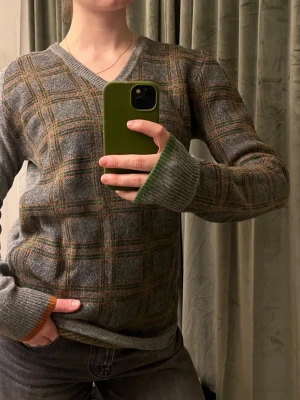 ulltröja Tiger of Sweden - Snygg grå tröja i 100 lammull från Tiger med rutigt mönster i grönt, orange och gult. V-ringad modell. Perfekt för dig som gillar klassisk men unik stil. Skulle säga liten i storleken (passar mig som vanligtvis är S/M