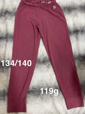 Mörkrosa fleecebyxor från Polarn O. Pyret - Mörkrosa fleecebyxor från Polarn O. Pyret med resår i midjan och raka ben. har en liten etikett med bokstaven P vid linningen. Perfekta för en chill och avslappnad look.🌸 Diffus fläck. Storlek 134/140 