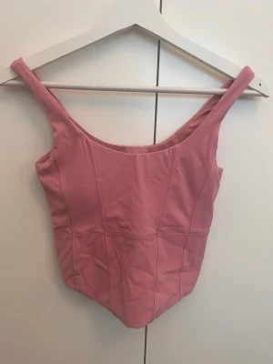 Tränings top  -  rosa tränings top  från Studio 1971 med breda axelband och sömdetaljer. Toppen är ärmlös och har en enkel, sportig design i stretchigt material som känns skönt mot huden. 