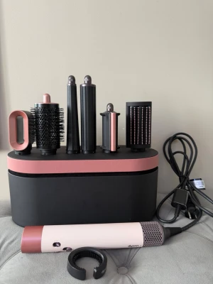 Dyson Airwrap complete long - Säljer ett Dyson Airwrap hårstyler set i svart och roséguld. Setet innehåller flera utbytbara tillbehör som rundborste, locktänger och borstar för olika stylingar. Allt kommer i en snygg förvaringsbox. Perfekt för att fixa håret snabbt och enkelt.