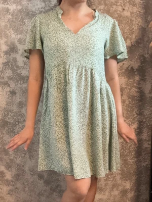 Miniklänning - Ljusgrön väldigt somrig miniklänning som har mönster med vitt bladverk. Storlek 36 från JDY. ✨Lätt och flowy material. ✨Köpt second hand. ✨Fläckfri.  Mina referensmått: Längd: 156 cm Byst: 87,5 cm Midja: 78 cm Höft: 93,5 cm