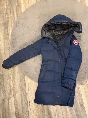 Mörkblå parkas från Canada Goose - Skitsnygg marin/mörkblå Shelburne Parka dam strl S från Canada Goose. Köpt på Johnells 2023, kan skicka äkthetsbevis om det önskas. Går för ca 17 000 orginalpris. Denna jacka är fint skick förutom några små fläckar (kom privat för fler bilder). Kemtvättad senaste vintern 😊 Kan gå ner i pris vid snabb affär