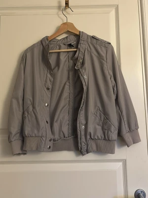 Ljusgrå bomberjacka  - Fin ljusgrå jacka i lätt material från H&M. Är i storlek 38. Ganska liten i storlek. Priset kan diskuteras. 