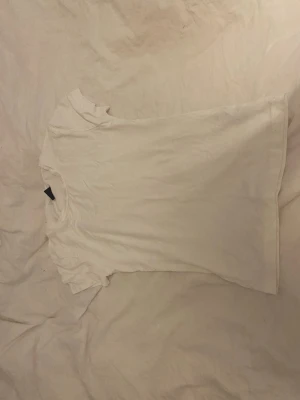 Vit basic t-shirt - En enkel vit t-shirt med rund hals och korta ärmar. Perfekt att matcha med jeans eller under en skjorta. Tillverkad i mjukt bomullsmaterial för en skön känsla hela dagen.